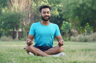 Meditasyonda oturan çekici Asyalı adam gün batımında park manzarasında yoga pozisyonunda pranayama dengesi kuruyor. Sağlık ve sağlık ve zindelik kavramı