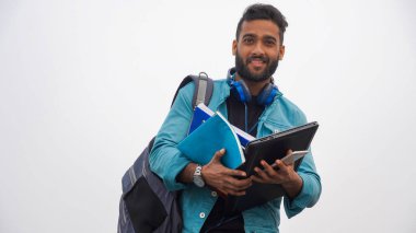 Dizüstü bilgisayarı ve kitapları olan genç sakallı Kolaj öğrencisi