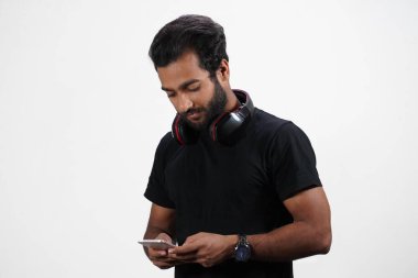 Bir adam kulaklığı beyaz arka planda olan bir cep telefonu kullanıyor