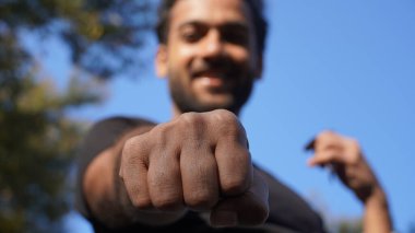 Hintli genç yakışıklı adam kameraya yumruğumuzu gösteriyor.