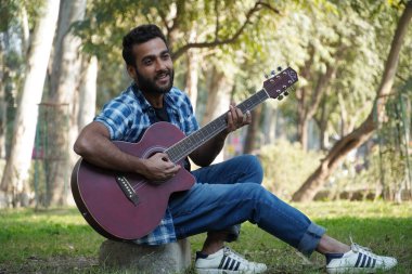 Gitarlı ve gitar çalan genç bir çocuk.