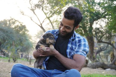 Parkta sevimli bir köpeği olan genç bir çocuk.