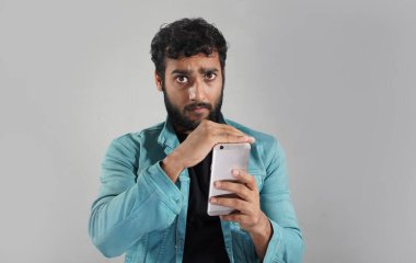 Çocuk cep telefonunu beyaz arka planda göstermekten memnun değil.