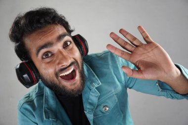 Beyaz arka plandaki stüdyoda kulaklık takıp video görüşmeleri sırasında yükseğe çıkmak...