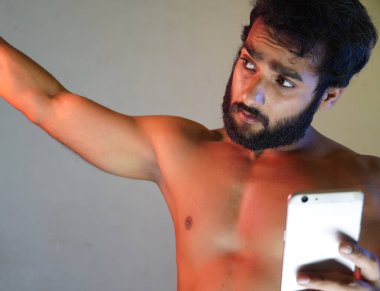 Telefonunu kullanarak selfie çeken sağlıklı bir adam.