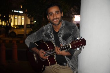 Genç gitarist gece geç saatlerde gitar çalıyor.