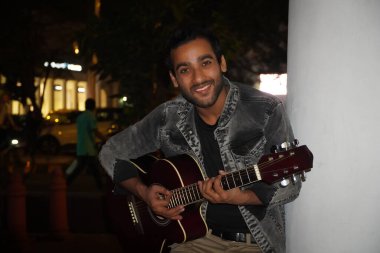 Genç gitarist gece gitar çalıyor. Yolculuğunun tadını çıkarıyor.