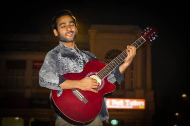 Gitarist görüntüsü, gitaristin kırmızı gitarıyla gitar çalıp eğlenmesi.