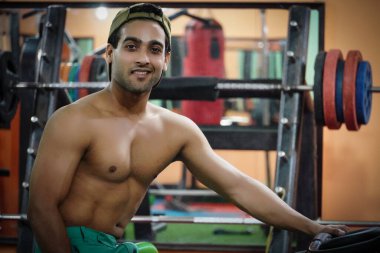 Genç adam spor salonunda bisiklete biniyor.