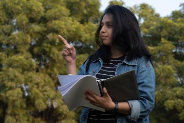 Bir şeyler gösteren kitapları olan üniversite öğrencisi.