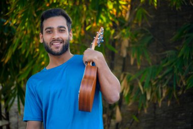 Ukulele 'li çocuk. Yakışıklı Hintli müzisyen imajı.