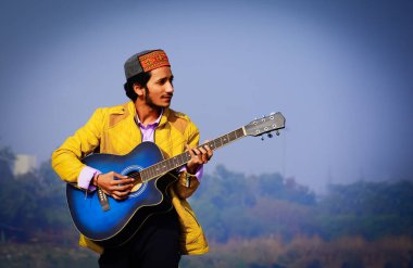 Adam teknede akustik gitar çalıyor..