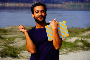 Sırt çantası ve kitaplarla gülümseyen genç üniversite öğrencisinin portresi.