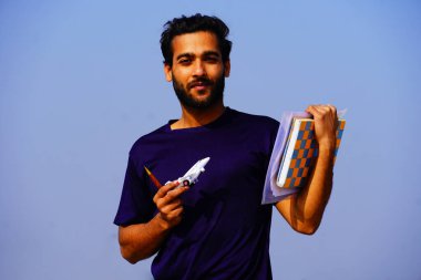 Sırt çantası ve kitaplarla gülümseyen genç üniversite öğrencisinin portresi.