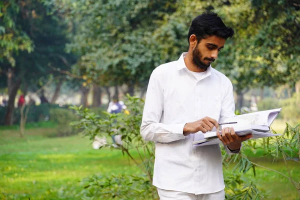 本のペンと大学のキャンパスの近くに立っているインドの少年 — ストック写真
