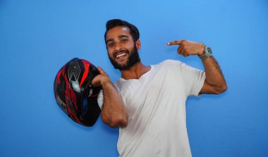 Adam ayakta ve elinde mavi arka planda izole edilmiş bir halet tutuyor