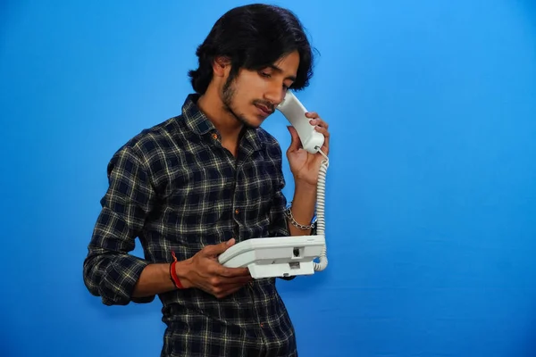 Yakışıklı Genç Adam Mavi Arka Planda Telefonla Konuşuyor — Stok fotoğraf