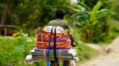 Kırsal kesimde bir adam bisikletten bir şeyler satıyor.