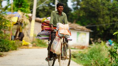 Kırsal kesimde bir adam bisikletten bir şeyler satıyor.