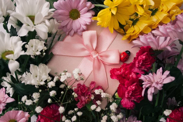 粉色礼品盒 五彩斑斓的花朵环绕 平躺在床上自然概念 — 图库照片