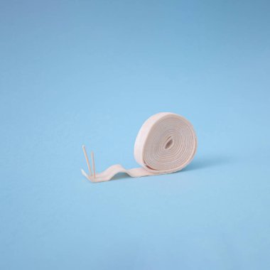 Açık mavi arka planda iki kürdanlı pastel pembe sakız rulosu salyangoza benziyor. Yan görünüm, ilginç bir kavram.