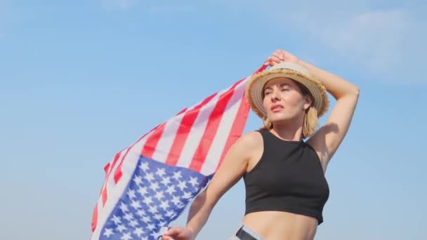 青い空にアメリカ国旗を掲げる若い女性の底面 スローモーションのポートレート アメリカでの休暇 独立記念日 — ストック動画