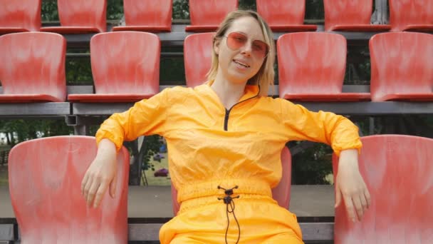 Young Woman Orange Suit Sits Stands Red Football Stadium Portrait — ストック動画