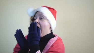 Kırk yaşında yetişkin bir kadın uyumak istiyor. Kırmızı Noel şapkalı sarışın bir kadının portresi. Ağır çekim. Yeni yıl tatili. Mutlu Noeller.