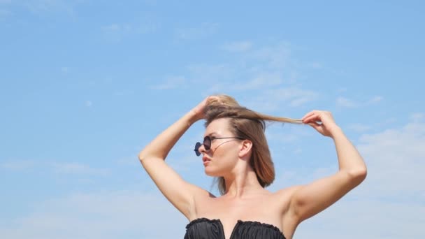 수영복을 하늘에 선글라스를 여성의 아래쪽 움직임의 손으로 머리를 만지는 — 비디오