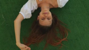 Yeşil arka planda beyaz elbiseli genç bir kadının portresinin üst görüntüsü. Kadın gülümsüyor