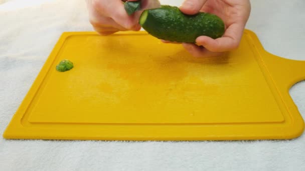 ナイフで男の手は緑のキュウリの皮を削除します スローモーション 野菜とサラダ — ストック動画