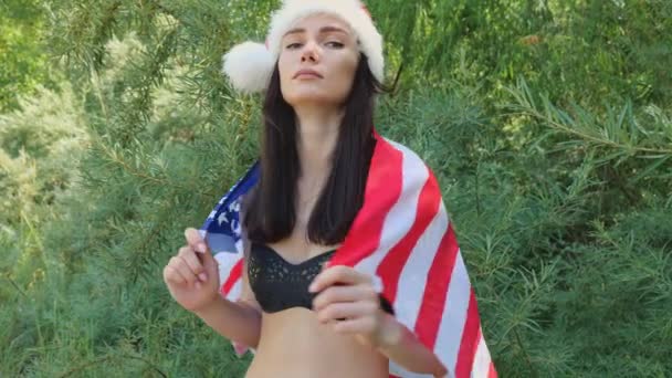 緑のジャングルの中の若いブルネットの女性の肖像 アメリカ国旗で笑顔の女性 7月4日独立記念日 — ストック動画