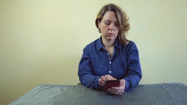 Czterdziestoletnia Kobieta Niebieskim Dresie Siedzi Przy Stole Telefonem Komórkowym Rękach — Wideo stockowe