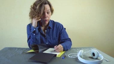 Kırk yaşında kot gömlekli bir kadın bir masada oturuyor ve cep telefonuyla konuşuyor. Yavaş çekim portresi