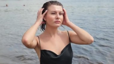 Suda siyah elbiseli, ıslak bir kadının portresi. Yavaş çekim portresi. Kadın denizde yüzüyor.