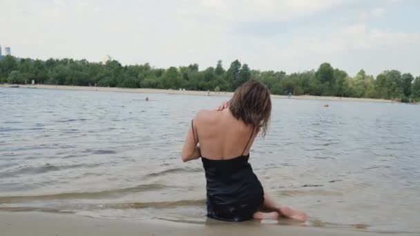 Visão Traseira Uma Mulher Vestido Preto Praia Perto Água Jovem — Vídeo de Stock