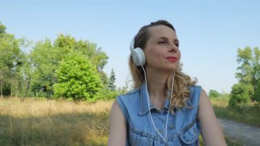Beyaz, geniş kulaklıklı bir kadının portresi. Kırk yaşında bir kadın müzik dinler. yavaş çekim