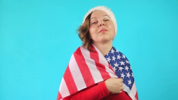 新年の帽子と赤いジャケットの美しい陽気な40歳の女性 アメリカ国旗を持つ成人女性の肖像画 独立記念日 — ストック動画