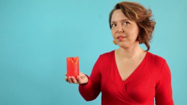 Kırmızı kazaklı, elinde mum tutan 40 yaşında bir kadının portresi. Mavi arka planda bir kadın. Sihirli kadın. Yavaş çekim 4k