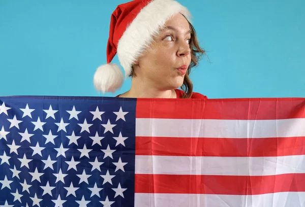 40 yaşında, yeni yıl şapkalı neşeli bir kadının portresi mavi arka planda Amerikan bayrağını taşıyor. Bağımsızlık Günü. Yeni Yıl