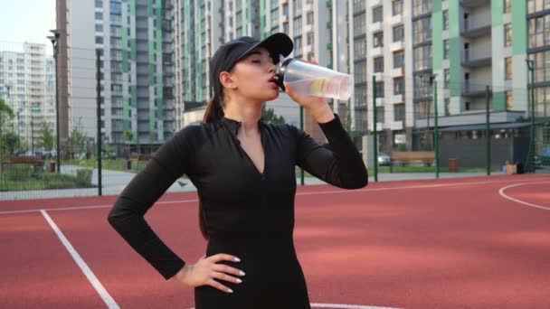 Young Athletic Woman Black Clothes Standing Stadium City Drinking Water — Vídeos de Stock