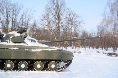 Side view of a military tank in a winter forest. Military equipment. War in winter