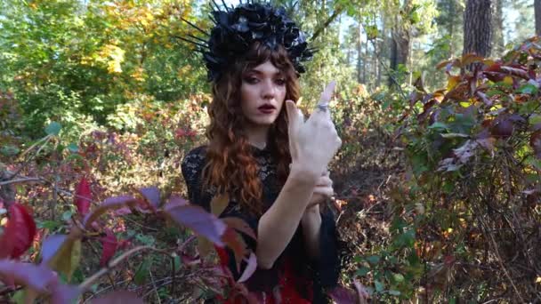 魔法の女性は 秋の紅葉の近くに立っている間 彼女の手に燃えるろうそくを保持しています ハロウィンの女 ハロウィンの肖像画 カーニバルの衣装を着た女 — ストック動画