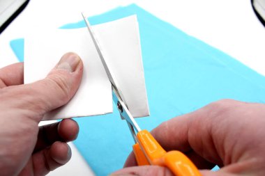 Eller makasla kağıt kesiyor.