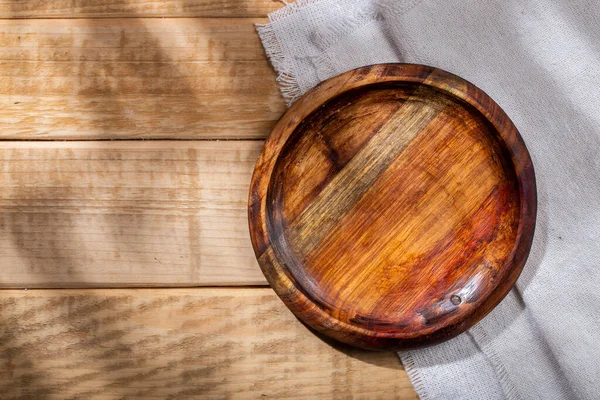 Circular shaped wooden bowl on the table, top view.