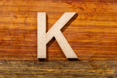 Wooden letters K on wooden background, top view