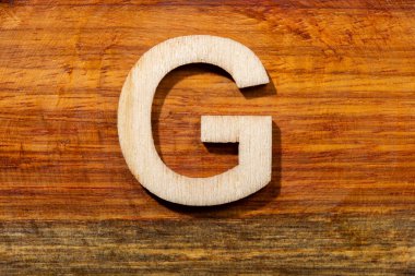 Wooden letters G on wooden background, top view