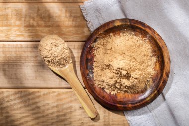 Maca powder, in wooden bowl on the table, nutritional substance from Peru.