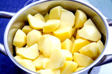 Paslanmaz çelik bir tencerede soyulmuş çiğ patates..