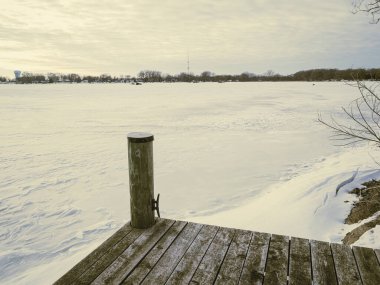Ahşap rıhtımdan soğuk mevsimde göl bulutlu bir gökyüzü ile donar..